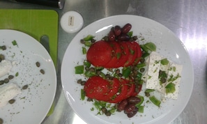 Two plates of food with tomatoes, olives, and cheese on a stainless steel surface. - Themonies Luxury Suites (Folegandros)