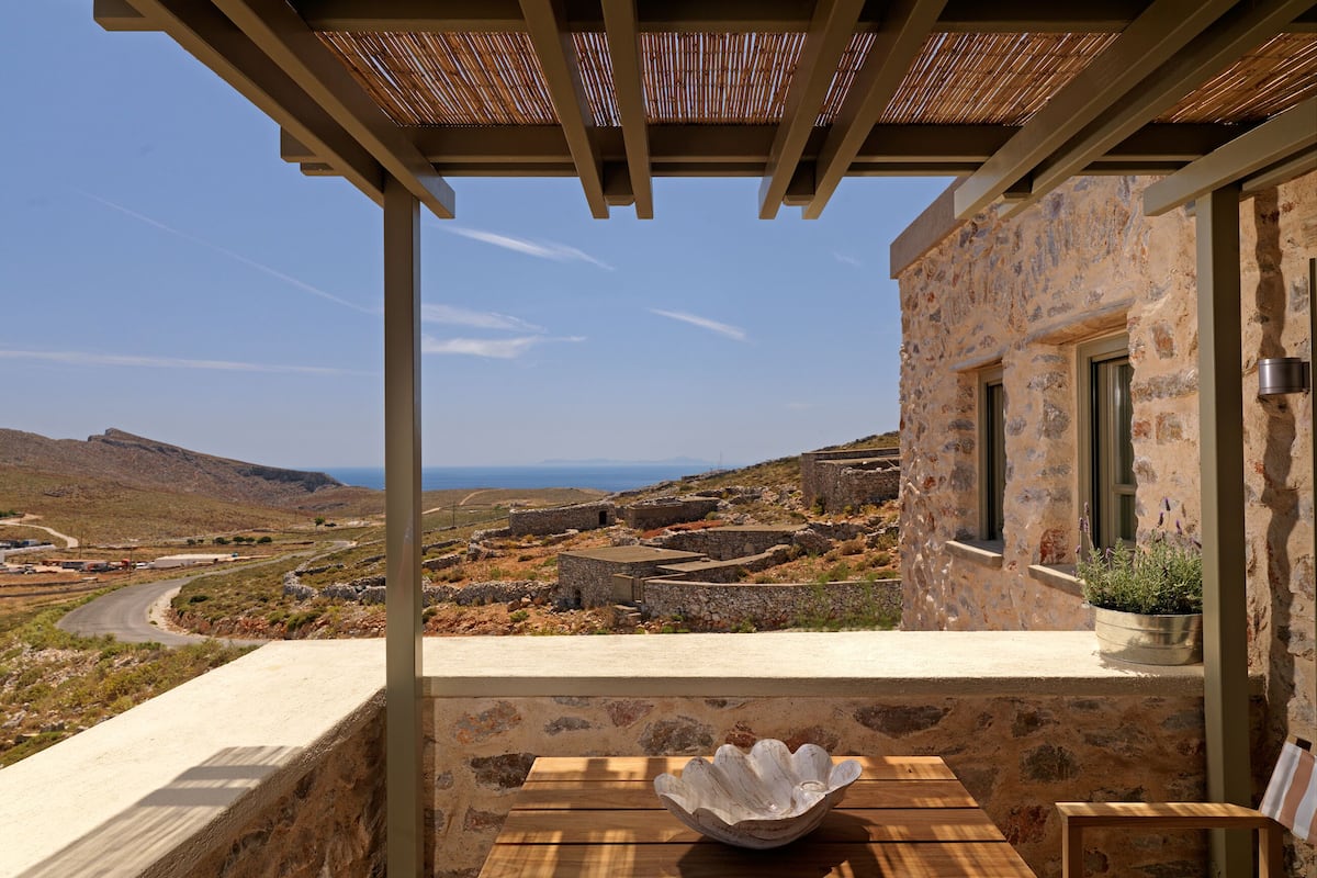 A stone building with a view of a rural landscape and the sea.