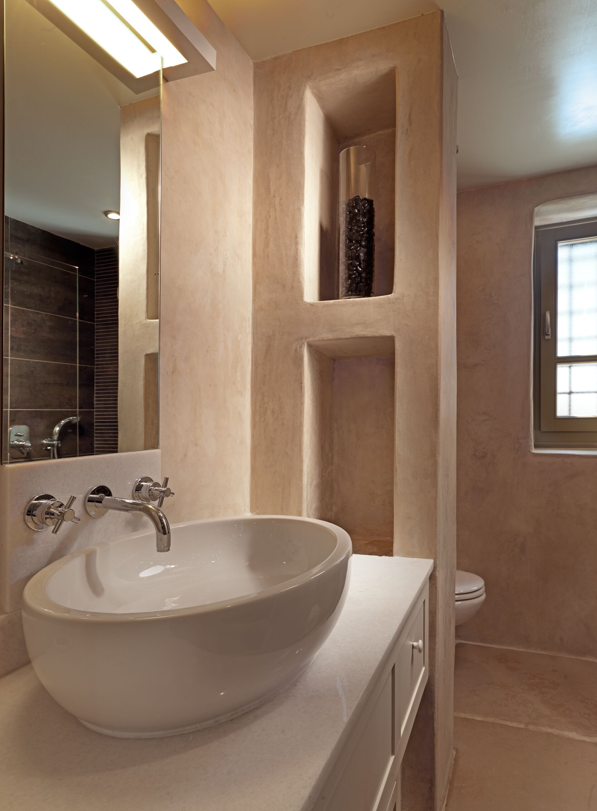 Un baño con un lavabo ovalado grande, un espejo y una ventana.