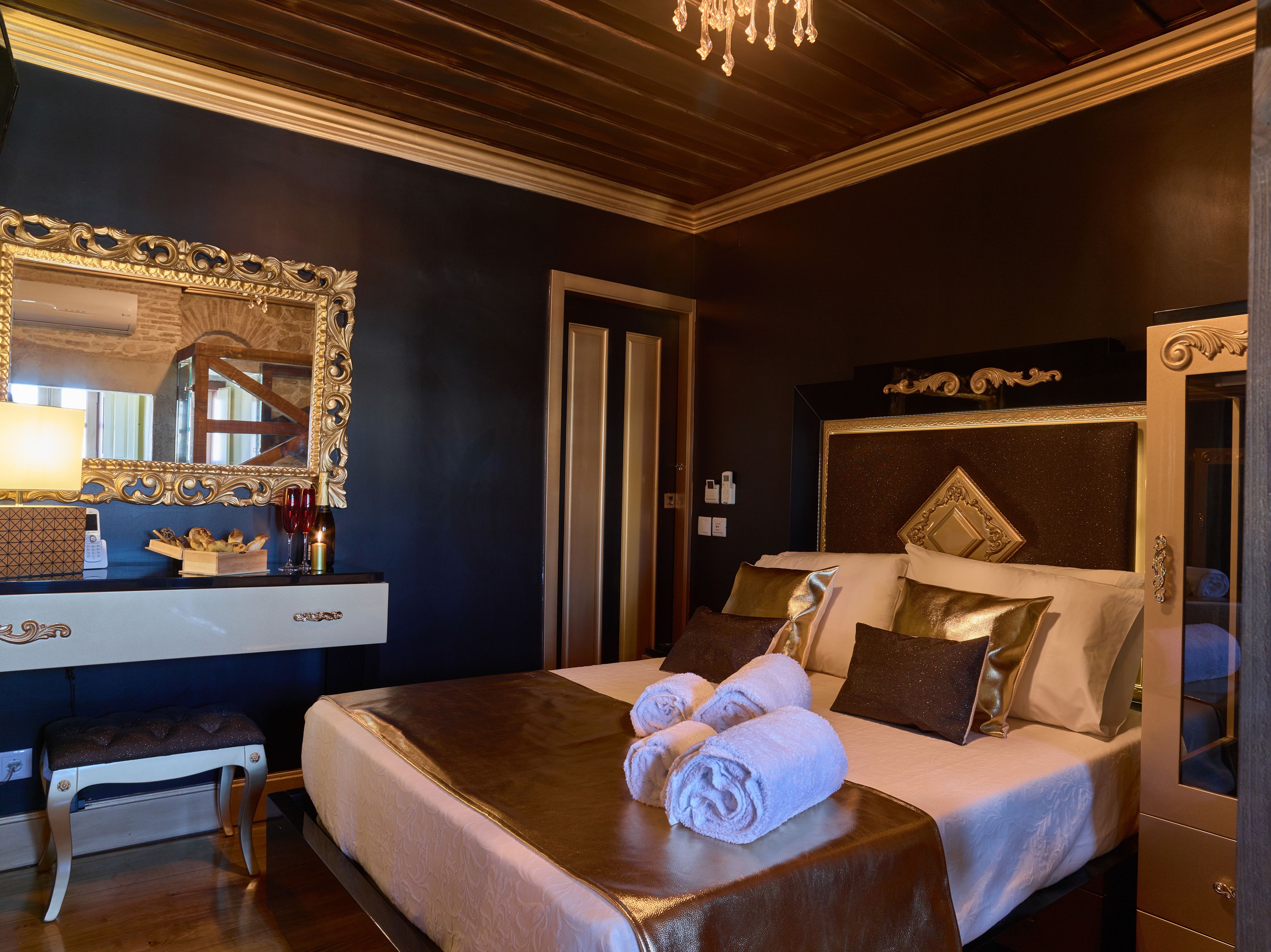 Une chambre d’hôtel avec un grand lit, une table de chevet avec une lampe, un miroir et un banc en bois.