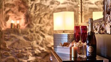 Une table avec une bouteille de vin Castello da Lapa, deux verres à vin rouge, une bougie allumée et un livre.