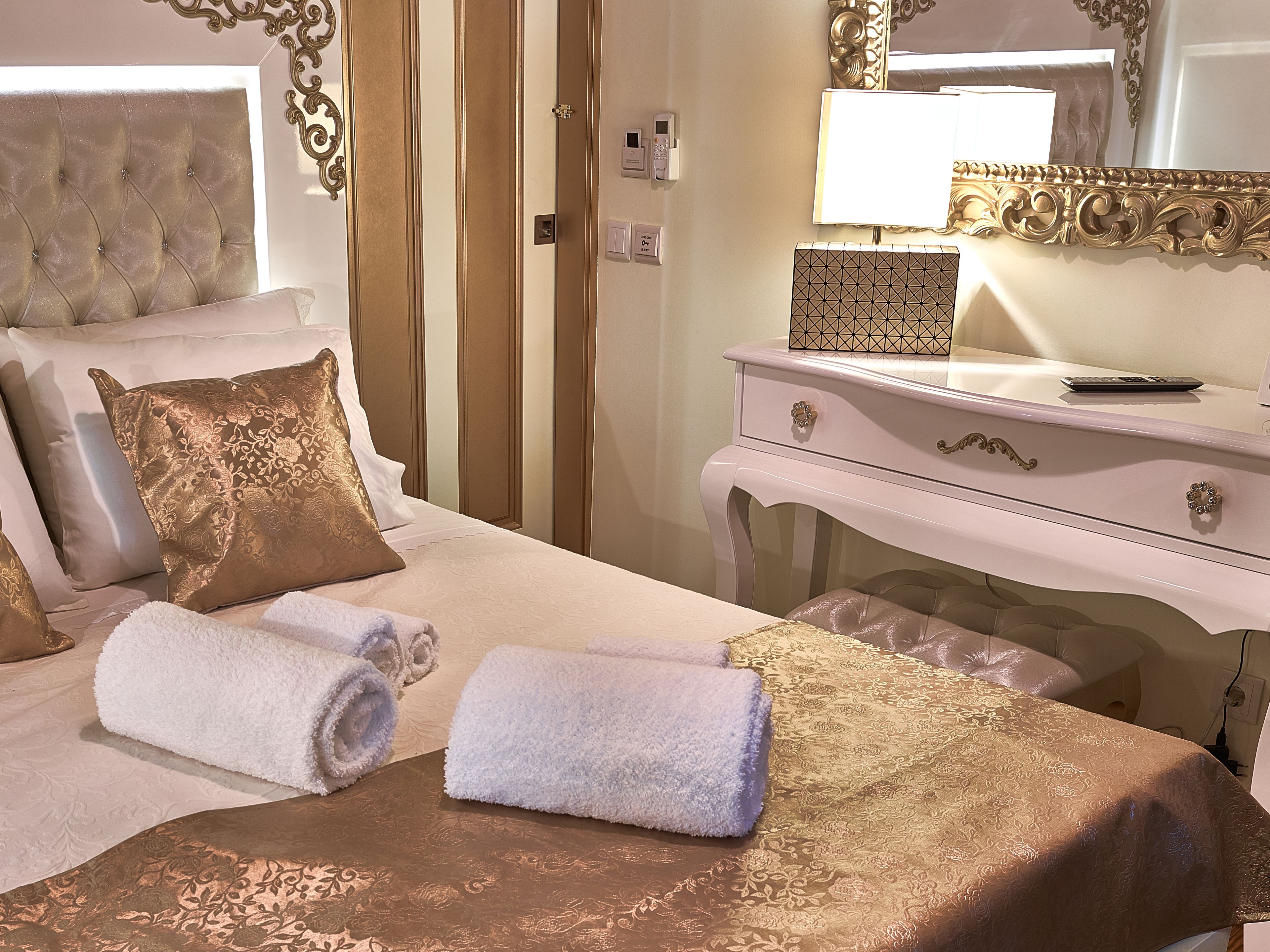 A hotel room with a bed, a dresser, a mirror, and a bedside table.