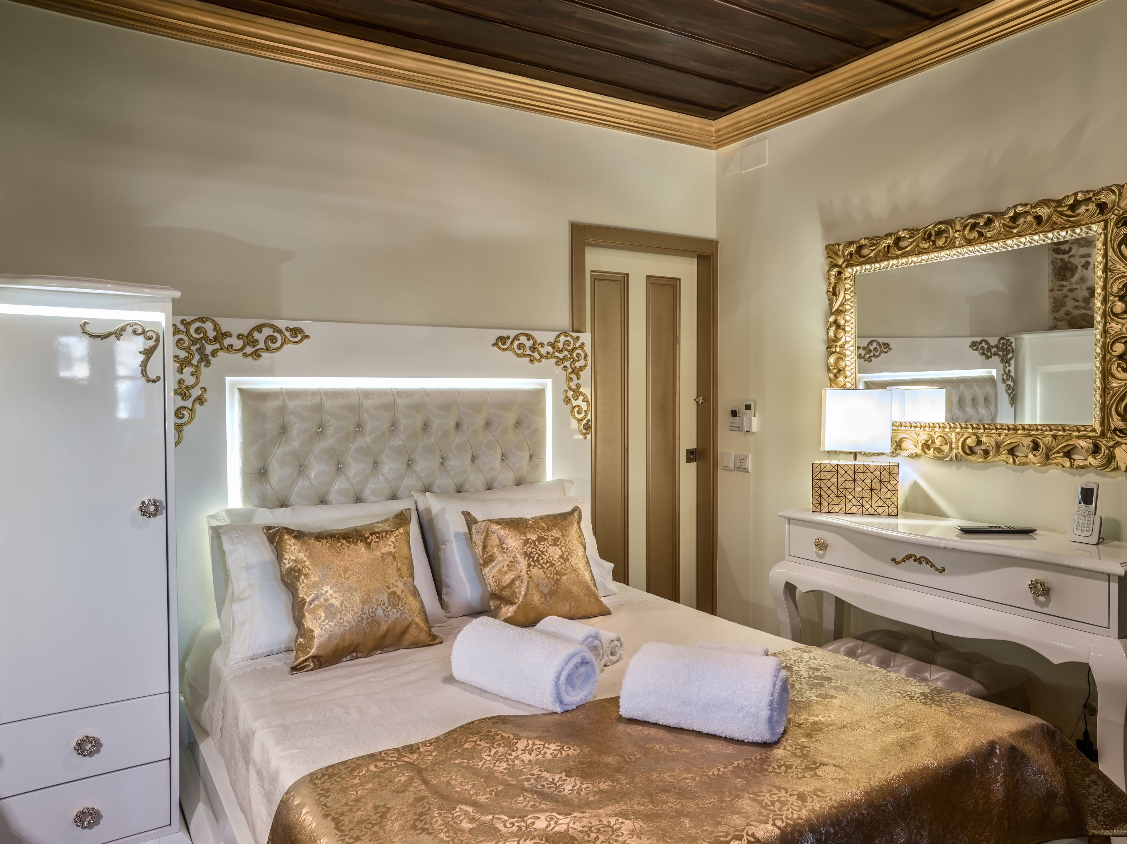 A hotel room with a large bed, a dresser, a vanity with a mirror, and a door.
