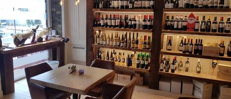 Una tienda de vinos con estantes llenos de botellas y una mesa con sillas.