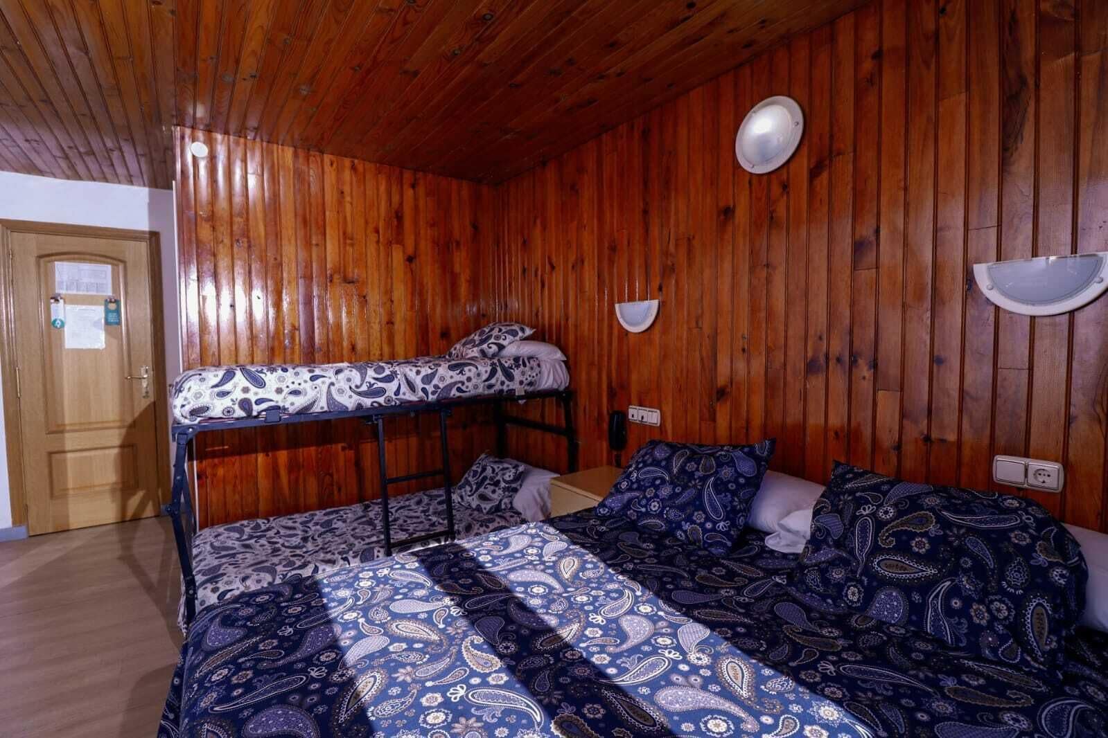 A room with wooden walls and a bunk bed.