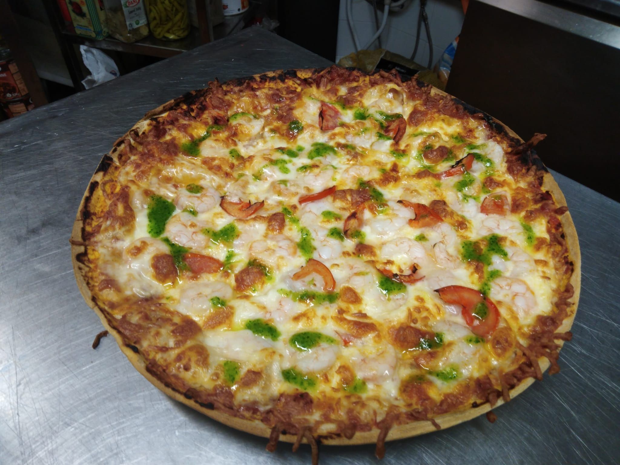Pizza con diferentes ingredientes sobre una superficie metálica.