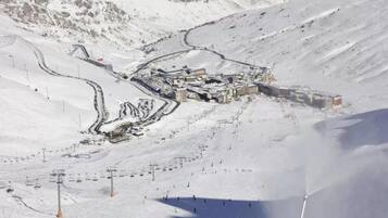 A snow-covered ski resort with ski lifts, a lodge, and a mountain backdrop.