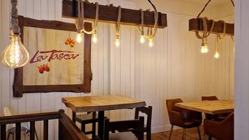 A restaurant interior with wooden tables and chairs, a wooden sign with 'La Tosca' written on it, and hanging light fixtures.