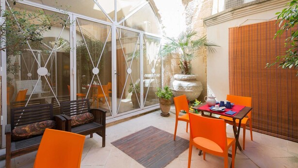 Une terrasse dotée d’une véranda en verre, de sièges d’extérieur et de plantes en pot.