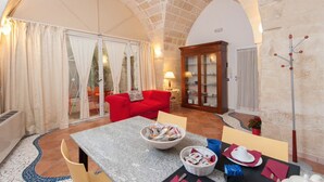 Une pièce chaleureuse avec un canapé rouge, une table à manger entourée de chaises, une cheminée et un grand plafond voûté en pierre.
