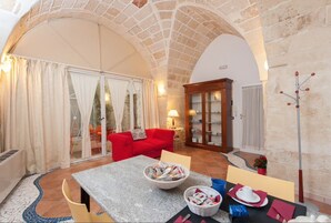 Una habitación acogedora con un sofá rojo, una mesa de comedor con sillas, una chimenea y un techo de piedra abovedado grande.