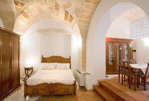 Un dormitorio con una cama de madera, una mesita de noche pequeña y una ventana.