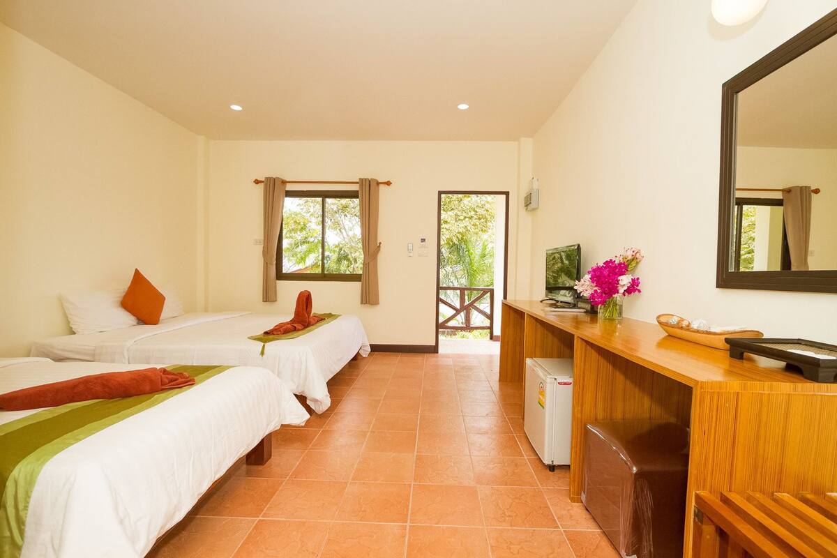 Une chambre d’hôtel avec deux lits, une petite kitchenette, un miroir et une vue sur l’extérieur.