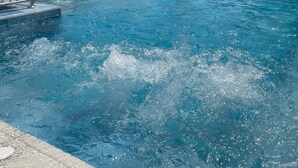 A swimming pool with lounge chairs and umbrellas, surrounded by buildings and palm trees. - Blue Garden Hotel (Konyaalti)