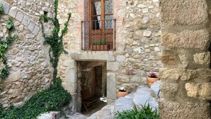 A stone building with a wooden balcony, a small entrance, and potted plants. - Hostal Can Xicu (Capmany)