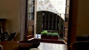 An open doorway leading to a stone building with a wooden window, a small table with a basket, and a chair. - Hostal Can Xicu (Capmany)