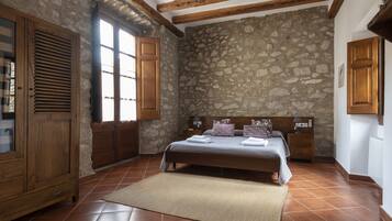 Un dormitorio con pared de piedra, estructura de cama de madera y un ventanal grande.