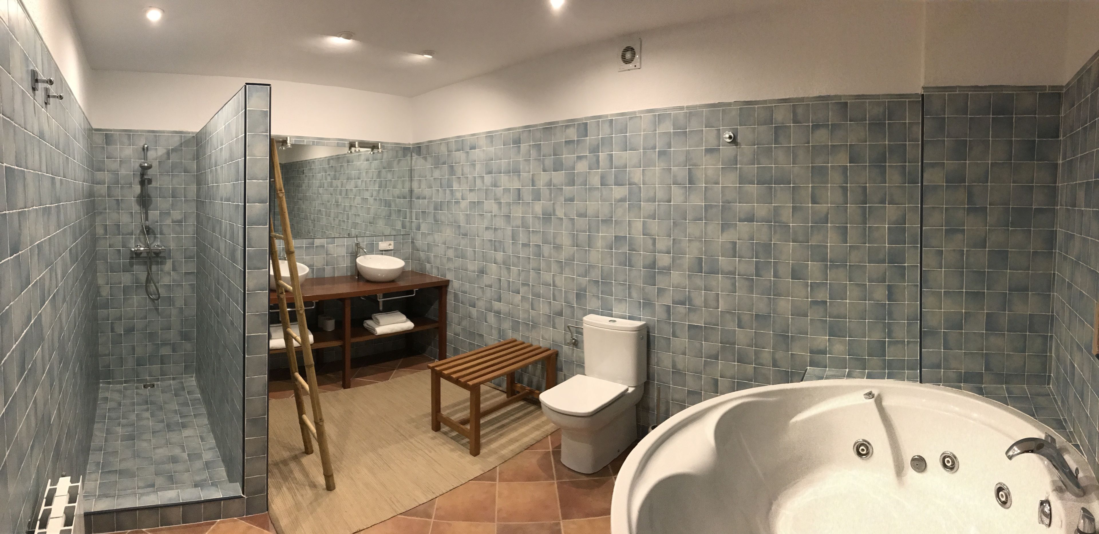 Un baño moderno con ducha a nivel, inodoro, lavabo y bañera.