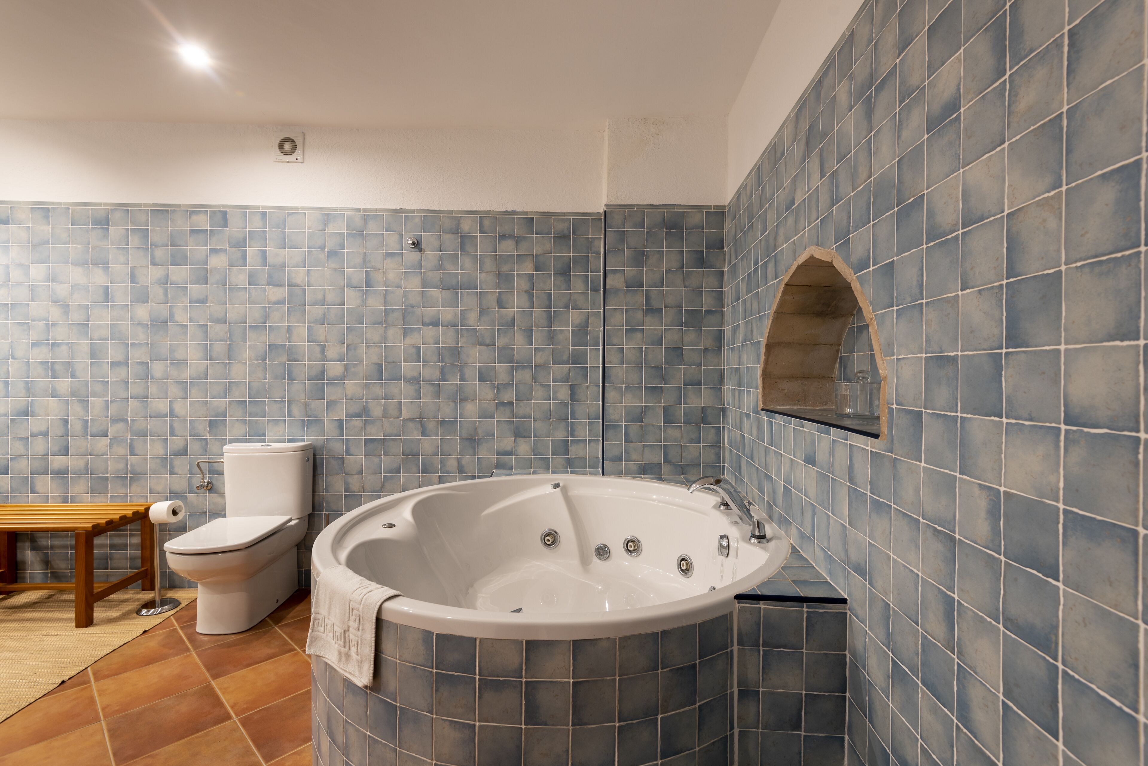 Ein Badezimmer mit Badewanne, Toilette und einer Sitzbank.