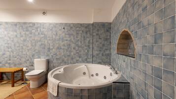 Ein Badezimmer mit Badewanne, Toilette und einer Sitzbank.