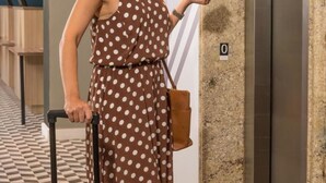 A woman in a polka dot dress standing next to an elevator, holding a card and a suitcase. - B&B Hotels São José dos Campos (São José dos Campos)