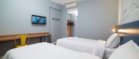 Habitación de hotel con dos camas, un televisor, perchero y escritorio de madera.