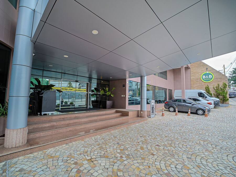 Entrada de un hotel con pavimento adoquinado, una escalera que conduce a la entrada y un coche estacionado.