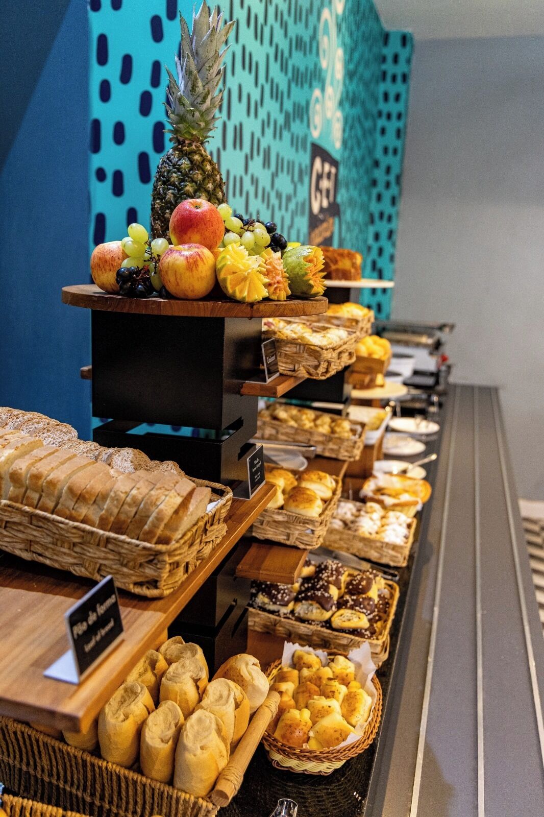 A buffet with various breads, pastries, and fruits.