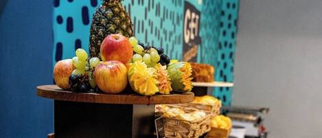 A buffet with various breads, pastries, and fruits.