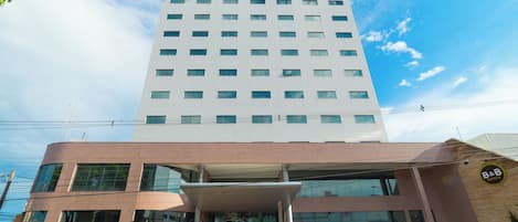 A modern hotel with a large entrance, multiple floors, and a clear sky.