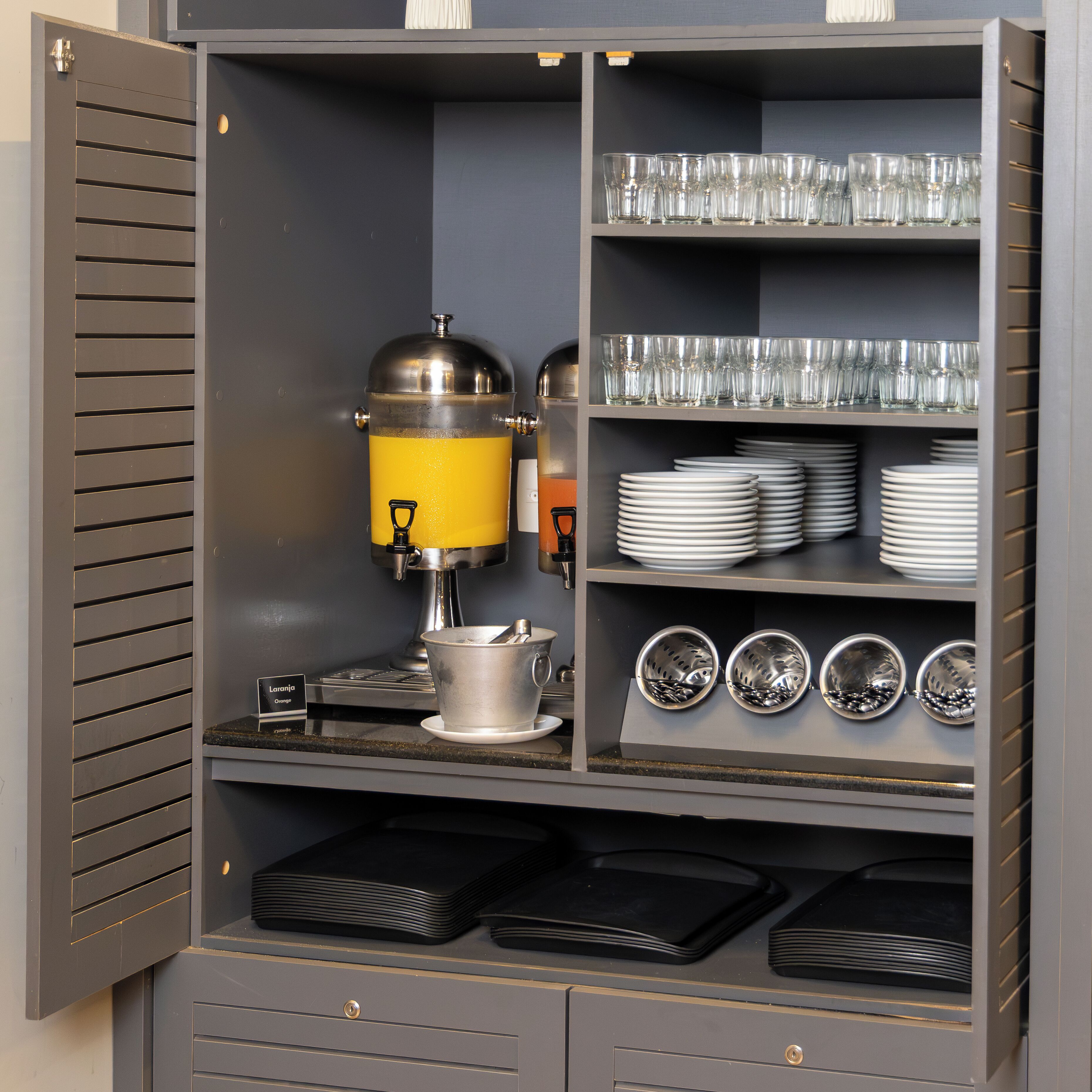 Una kitchenette con cafetera, platos apilados y cristalería.
