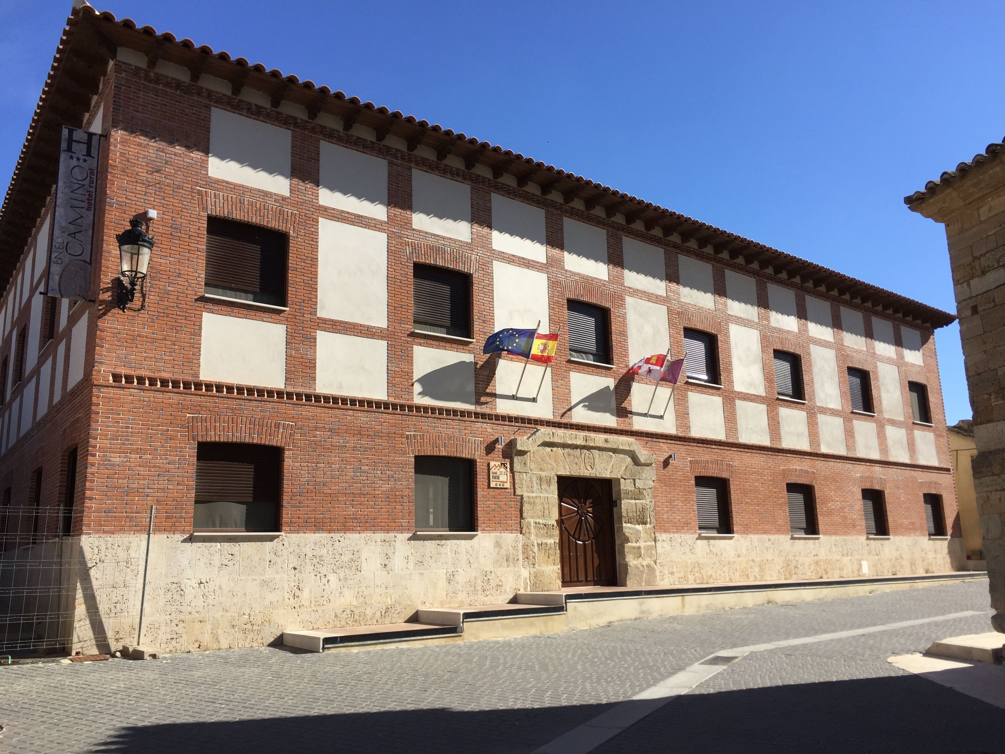 A historic building with a checkered facade, a central entrance with a large wooden door, and multiple windows.