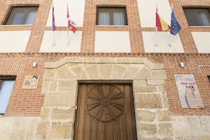 A building with a large wooden door, multiple windows, and flags.