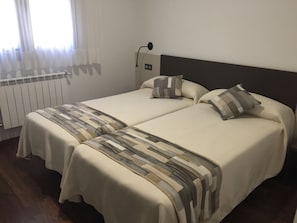 Ein Doppelbett mit gestreifter Bettdecke, ein Nachttisch und ein Beistelltisch.