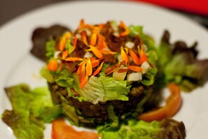 A close-up of a salad with various vegetables and a leafy base. - O Chardinet d'a Formiga (La Fueva)