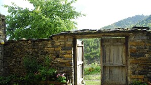 A rustic stone building with a wooden door and a stone archway. - O Chardinet d'a Formiga (La Fueva)