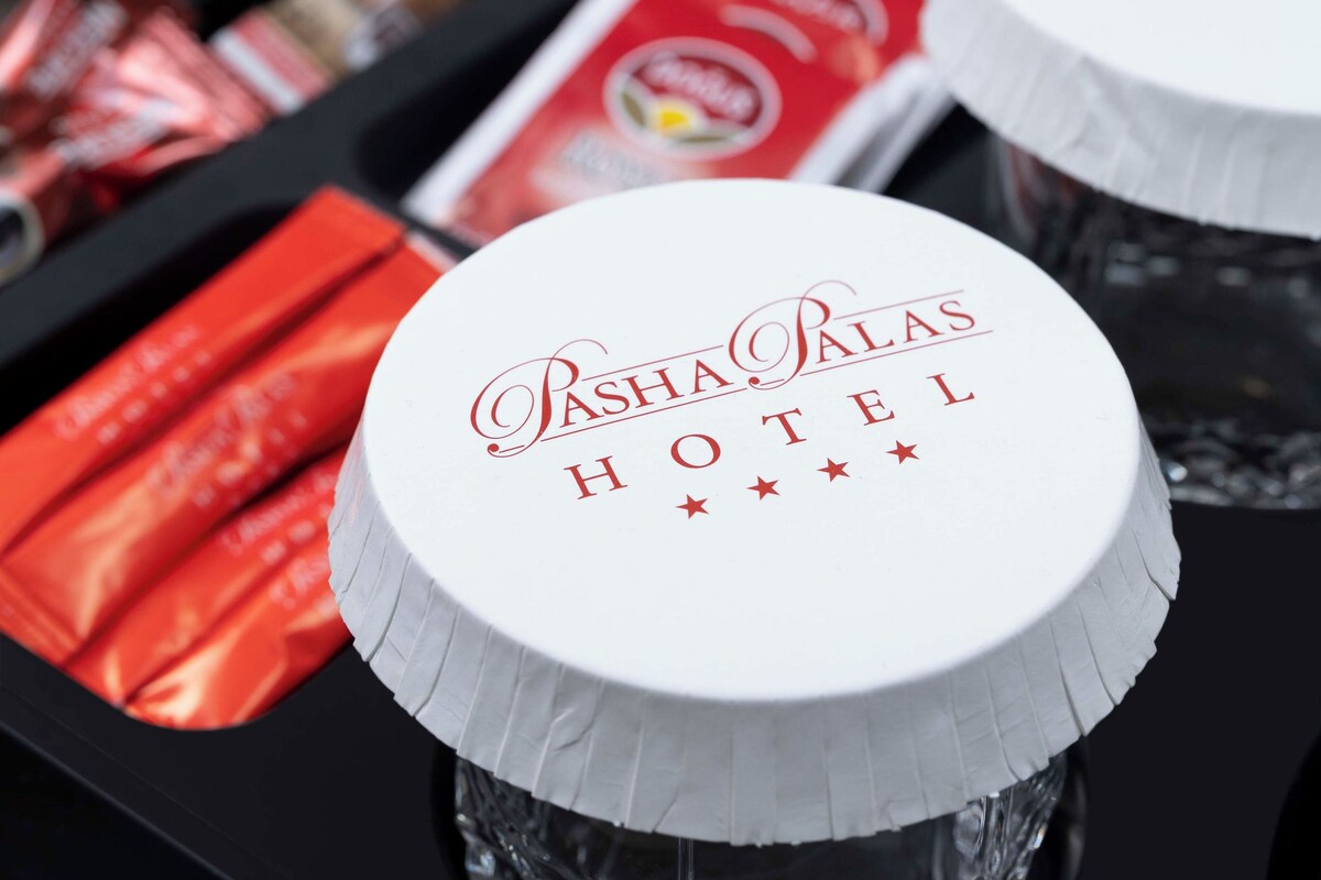 A tray with two glass bottles labeled 'Pasha Palas Hotel' and a set of red packets, possibly snacks.