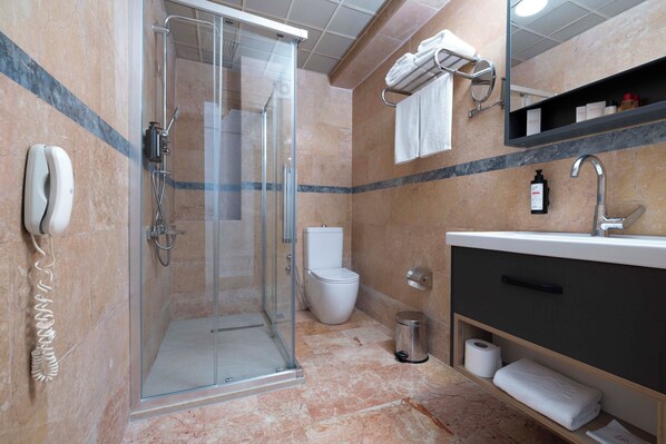 A modern bathroom with a glass-enclosed shower, a toilet, a sink with a mirror, and a towel rack.