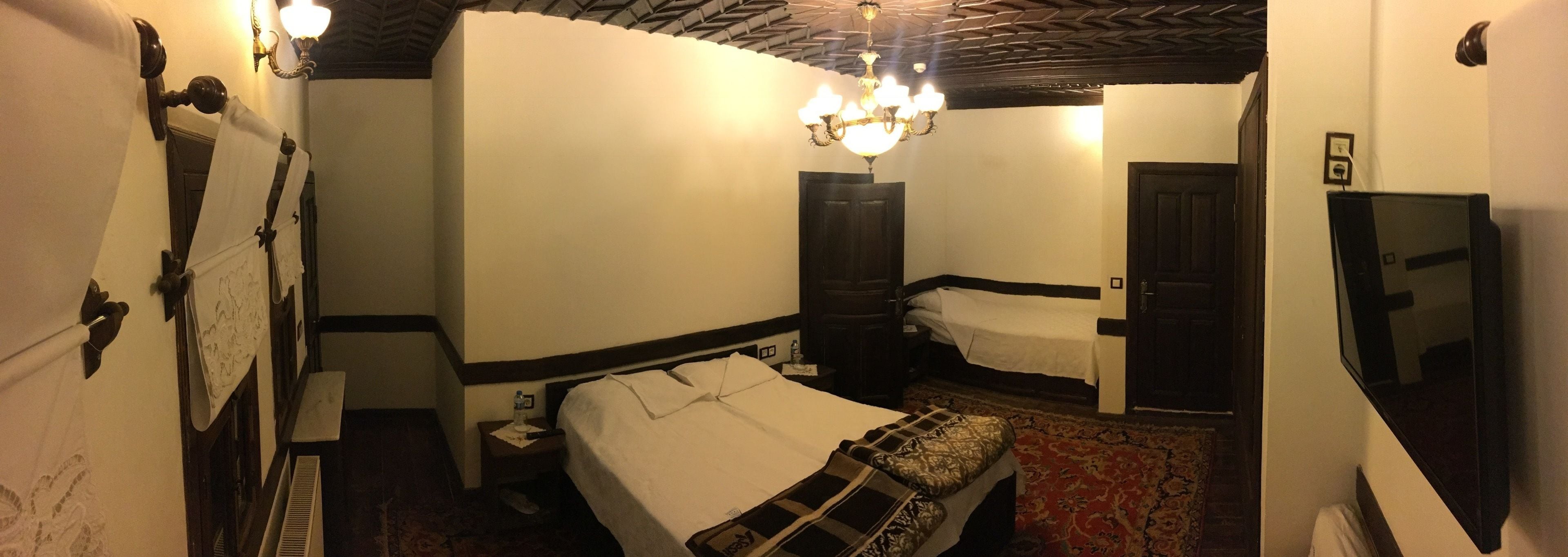 A hotel room with a bed, bedside table, lamp, and a mirror.