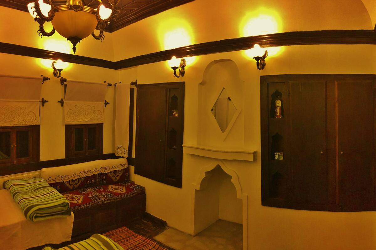 A traditional room with a bench, a mirror, and a door with a decorative arch.