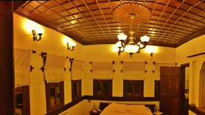 Una habitación de hotel con techo alto, una araña, cortinas de encaje y una cama.
