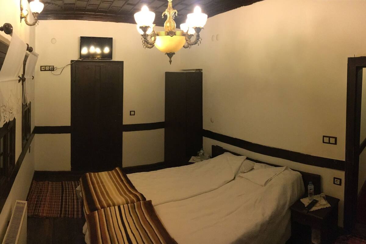 A narrow hallway with a bed on the right, a door at the end, and a TV on the wall.