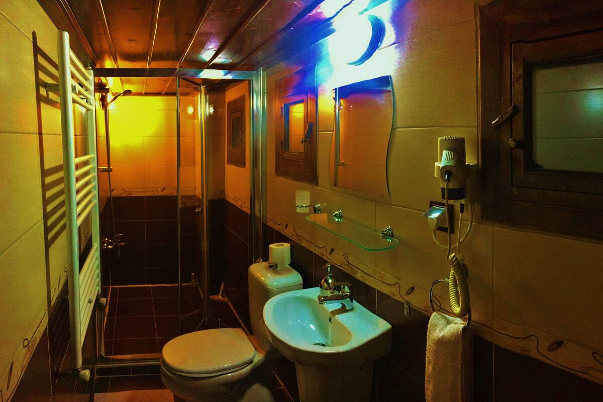 A compact bathroom with a toilet, sink, and glass shower enclosure.