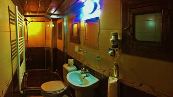 A compact bathroom with a toilet, sink, and glass shower enclosure.