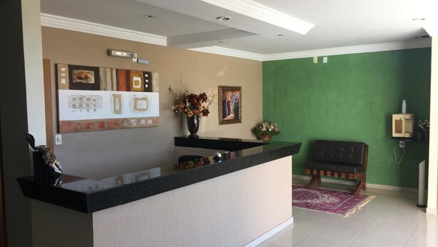 A reception area with a counter, a green wall, and a sofa. - Trindade Hotel (Trindade)
