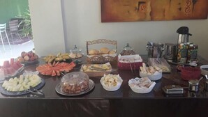 A buffet table with various food items and condiments. - Trindade Hotel (Trindade)