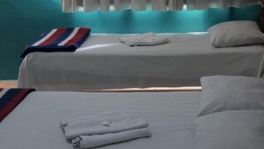 A hotel room with two beds, a window with curtains, and a teal wall. - Trindade Hotel (Trindade)