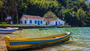 Un bote anclado a un muelle, con una casa al fondo.