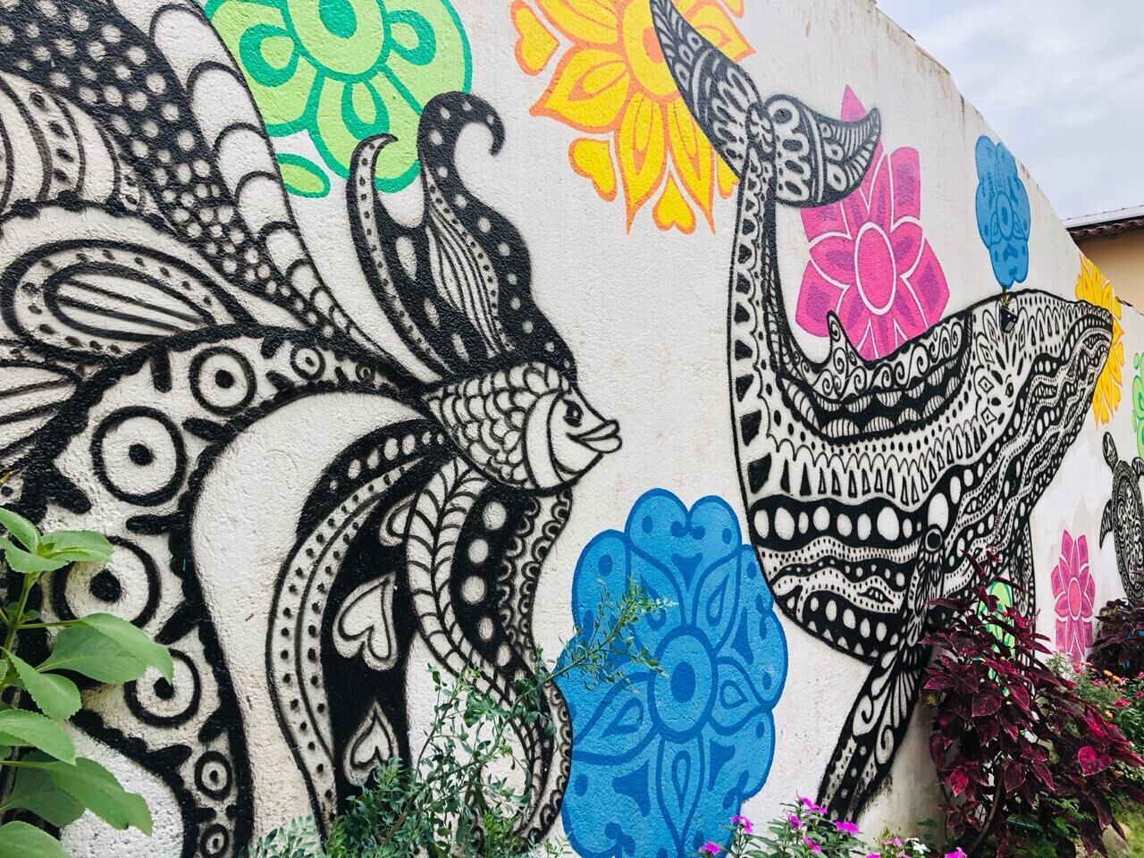 Un mur orné d’une grande fresque colorée représentant des oiseaux et des motifs floraux.