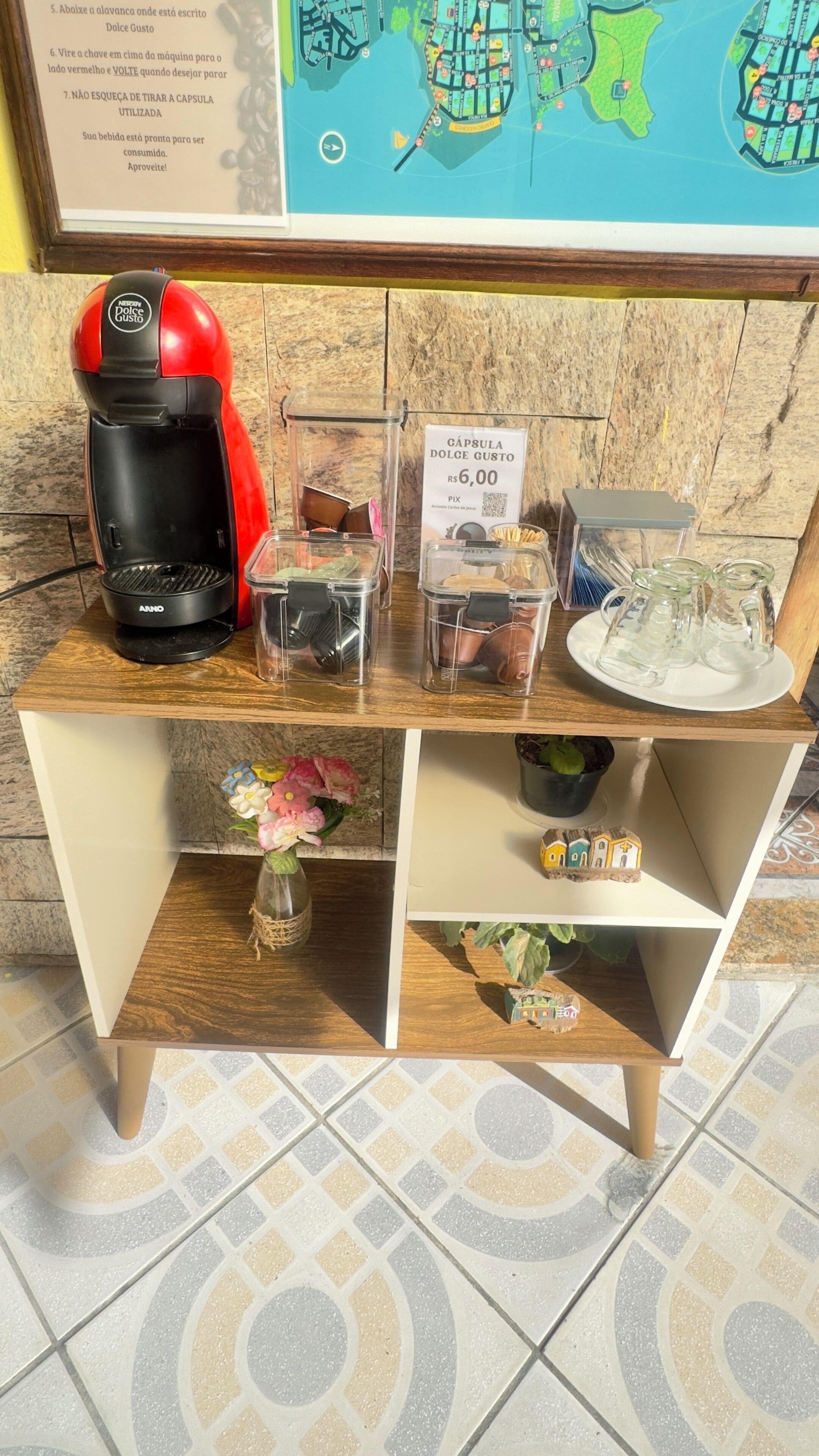 A coffee station with a red coffee maker, disposable cups, and a sign indicating a price of Rs. 6.00 for a cup.